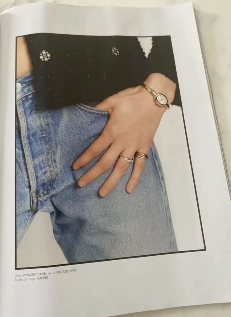 Person iført vintageklær fra Chanel og Levi's, smykker fra Cartier, med en hånd i lommen på et par jeans.